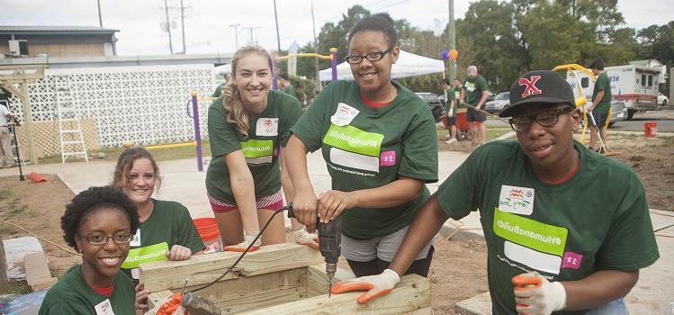 five service volunteers wearing green Humana Builds t-shirts on building site